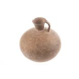A Persian antique single handle terracotta vessel of bulbous form with flared rim and stippled