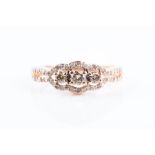 A white and cognac diamond ring centred with three round-cut cognac diamonds, the openwork border