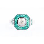 A diamond and emerald ring in the Art Deco style, the square chamfered mount centred with an old-cut