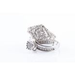 A white metal and diamond accent crossover ring centered with a raised cluster of round-cut