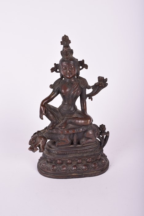 A South East Asian bronze deity, possibly Tara the goddess sits above a crouching guardian, raised