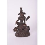 A South East Asian bronze deity, possibly Tara the goddess sits above a crouching guardian, raised