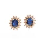 A pair of 18ct yellow gold, diamond, and sapphire earrings of oval cluster form, the stems marked