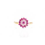 A yellow metal, diamond, and pink sapphire cluster ring set with round-cut sapphires and small