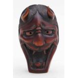 Masken-Netsuke.Buchsbaum, fein geschnitzt (min. besch.) unt tief rot eingefärbt. Hannya-Maske mit