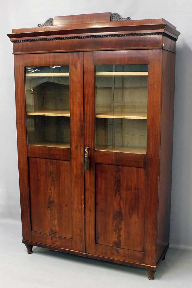 Biedermeier-Bücherschrank.Mahagoni, über Nadelholzkorpus furniert. Hoher, schmaler, zweitüriger