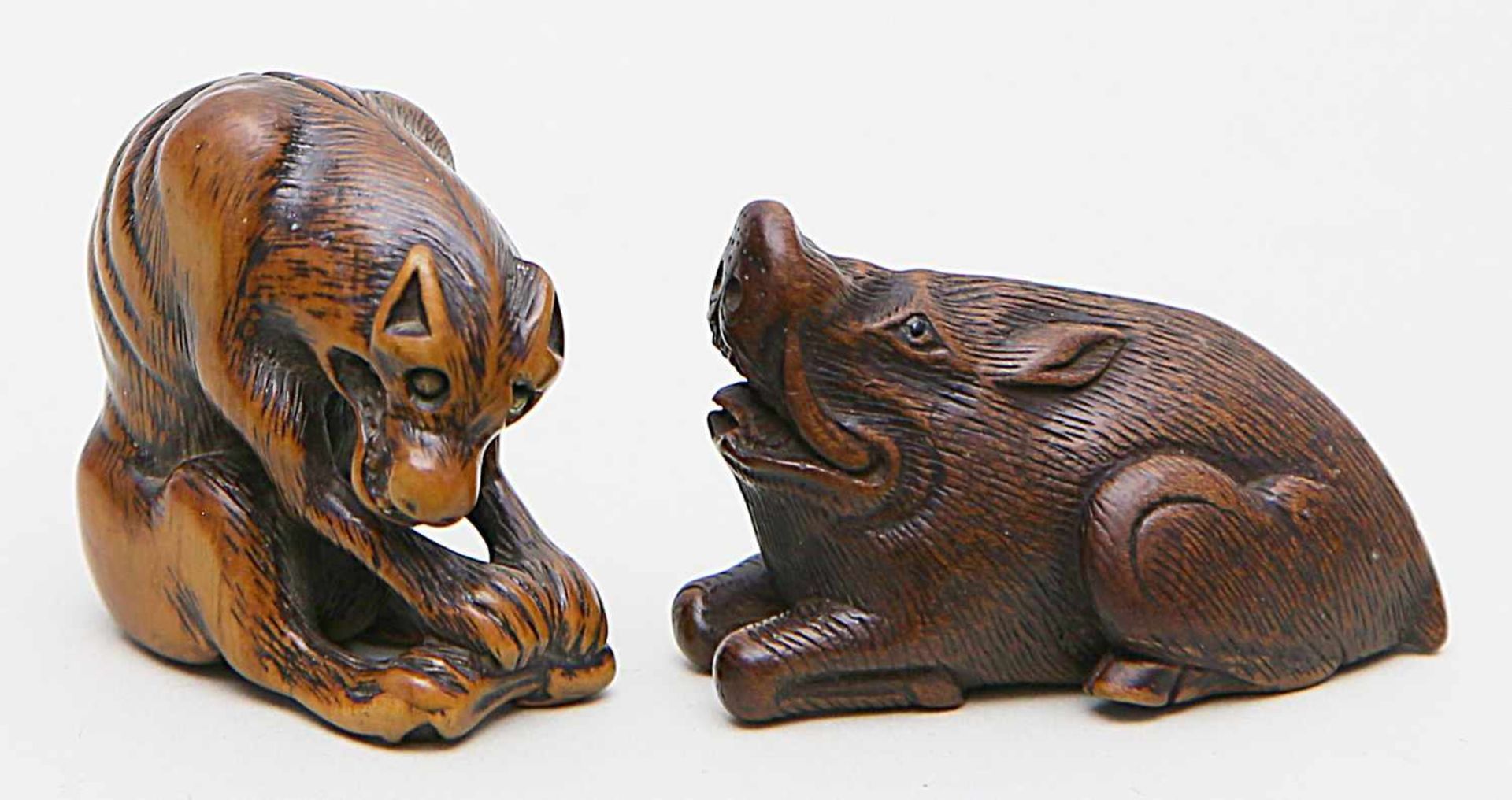 Zwei Netsukes.Eber und abgemagerter Wolf (okami) mit Rehkeule. Buchsbaum/Holz, teils dunkel