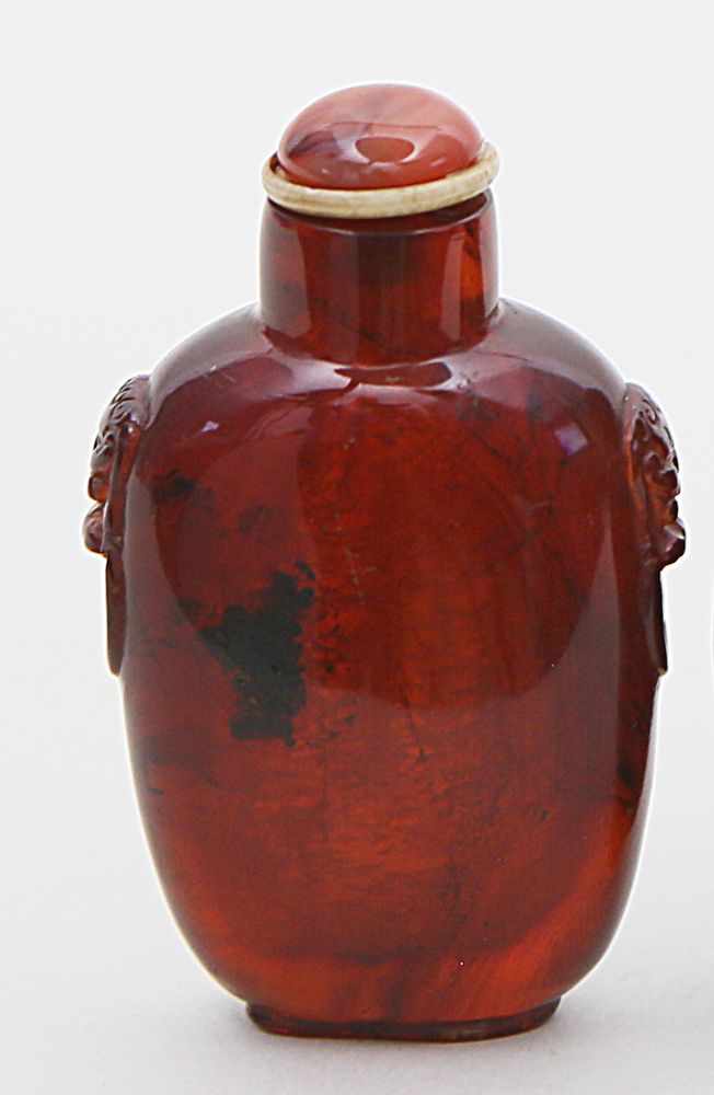 Snuffbottle.Bernstein (Amber). Gestreckte Eiform, an den Schultern Ringmasken. Karneolstöpsel.