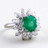 Damenring.750/000 WG, brutto 9,6 g. Blütenförmiger Ringkopf, besetzt mit Smaragd im Emeraldcut (