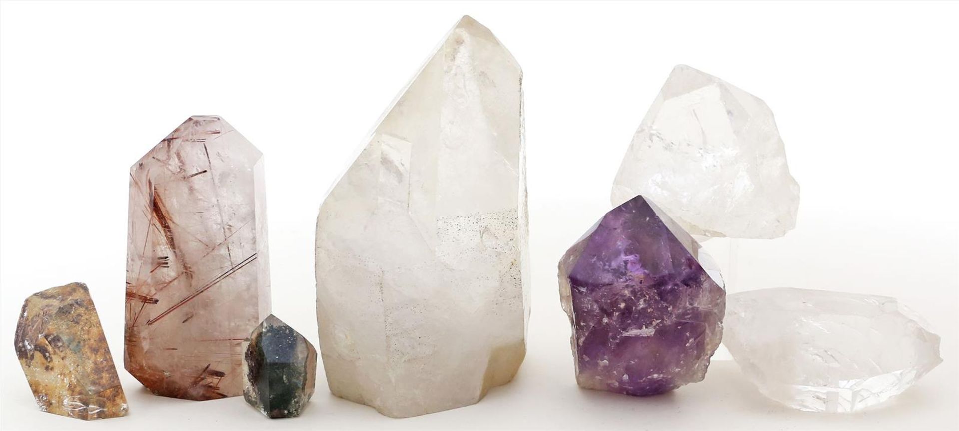 7 Kristallspitzen vonBergkristall und 1x Amethyst, teils mit Einschlüssen anderer Mineralien. L. 3,5