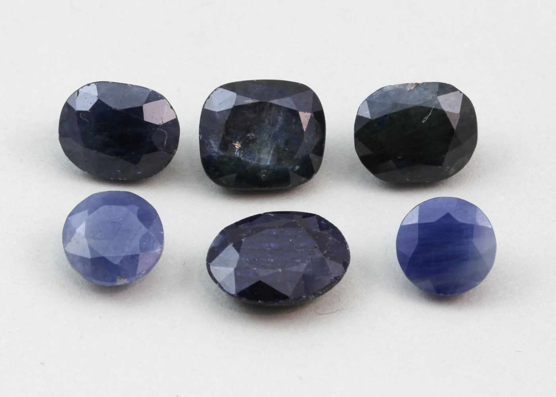Sechs blaue Saphire, zus. 26,9 ct.Oval bzw. rund facettiert. Verschiedene opake Farbnuancen. Teils