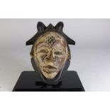Houten gestoken Punu masker met spleetogen en gesloten mond, bekroond met horens, Gabon, l. 30 cm.