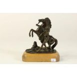 Bronzen sculptuur van steigerend paard met menner op houten voet, h. 13 cm.