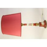 Porseleinen Limoge tafellamp met decor van figuren in landschap met rood stoffen kap, h. 90 cm.