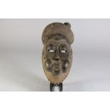 Houten gestoken Baule masker met open ogen en blazende mond, Ivoorkust, l. 29 cm.Wooden carved