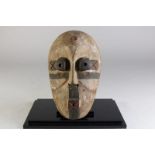 Houten gestoken deels polychroom Tatela masker met ronde ogen en fluitende mond, Kameroen, l. 29