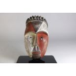 Houten gestoken deels polychroom Mvoudi masker met vierkante ogen een gesloten mond, Gabon, l. 37