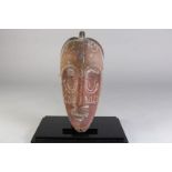 Houten gestoken Fang terracotta kleurig masker met spleetogen en gesloten mond, Gabon, l. 35 cm.