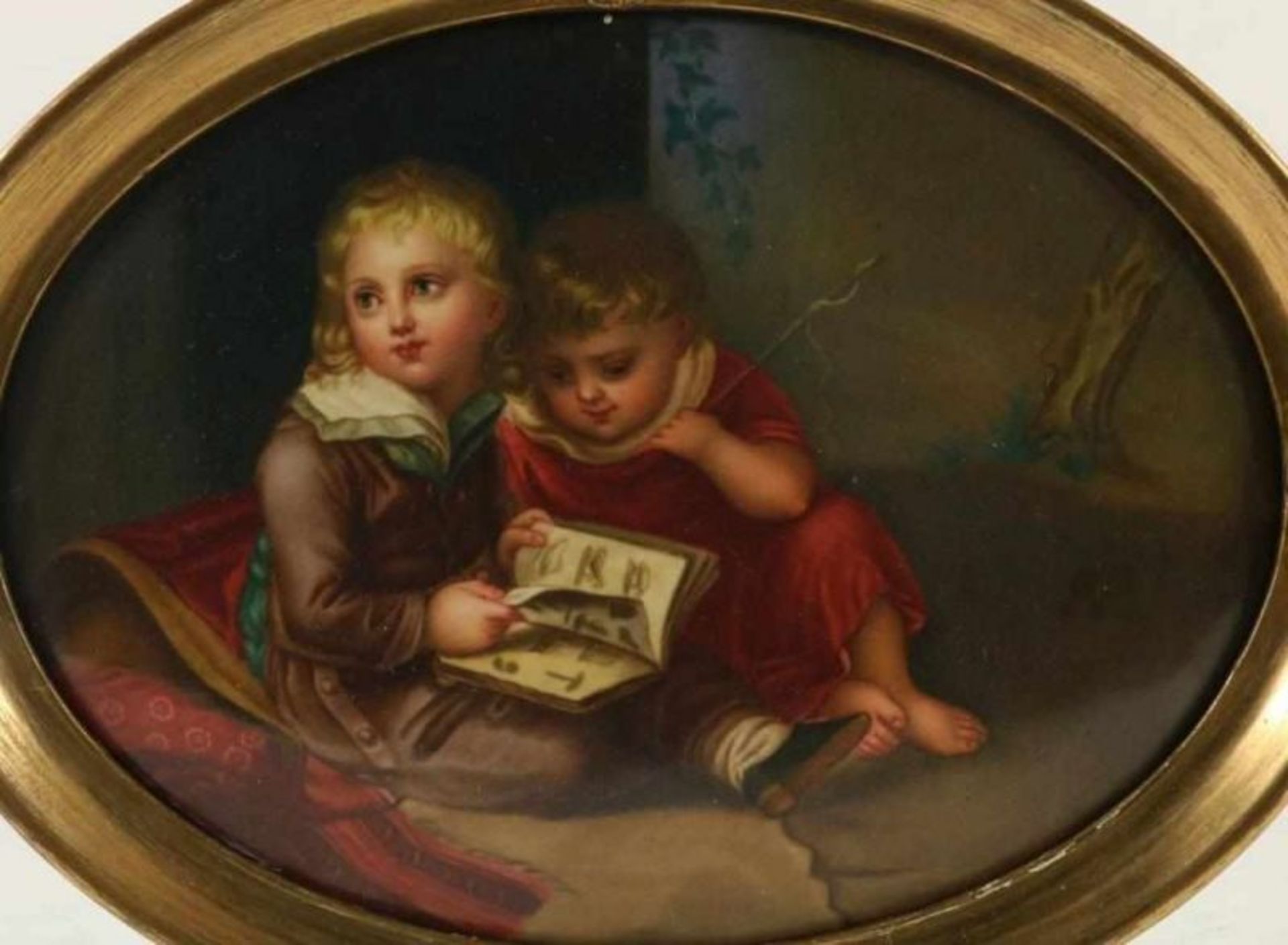 Porseleinen ovale plaquette met decor van 2 lezende kinderen, 20 x 26 cm.