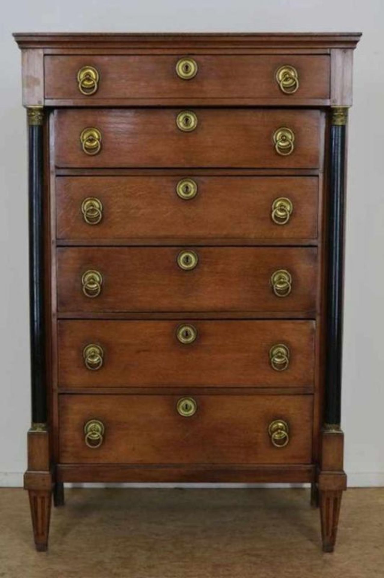 Eiken Empire chiffonnière met 6 laden en geflankeerd door zuilen op taps toelopende poten, ca. 1820,