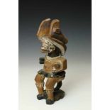 Nigeria, Ibo, wooden seated Ikenga figurewith painted facial accents and carved head in left hand.