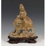 China, spekstenen snijwerk;Guanyin gezeten op kylin. Op bewerkt houten voet; h. 25, br 20 cm.