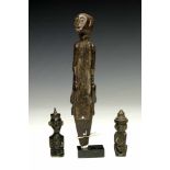Borneo, East Kalimantan, two wooden amulets of squatting male figuresand an implement of a squatting