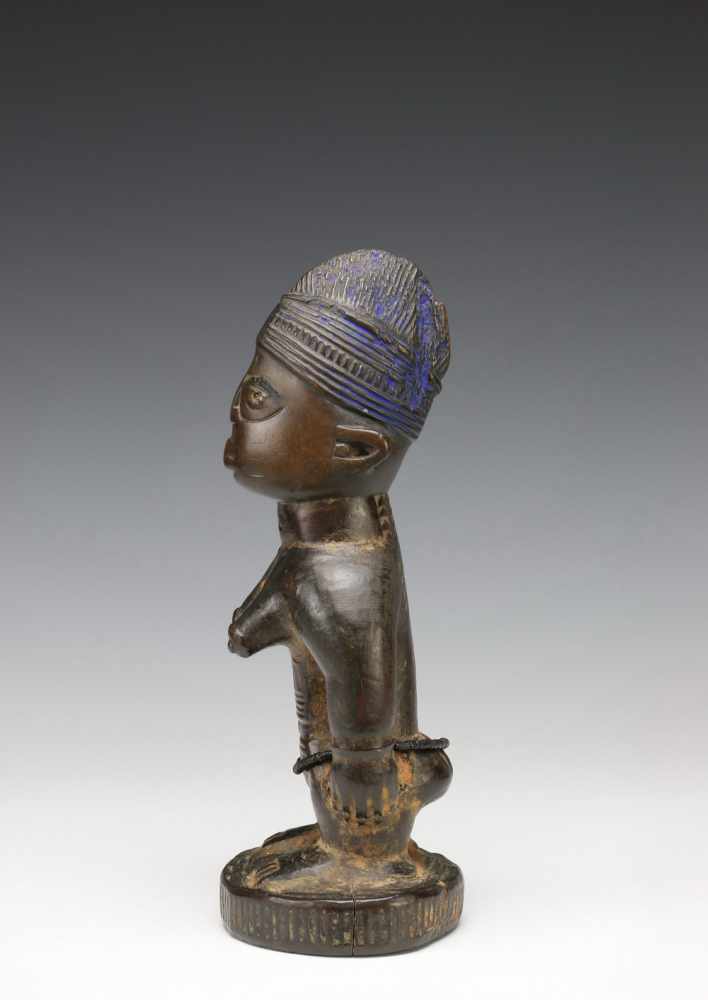 Yoruba, standing female Ibeji figurewith rows of scarifications on the body and brown to black