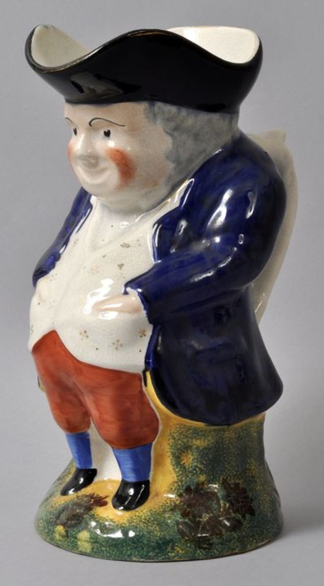 Figurenkrug/ Toby Jug, 19./ 20. Jh.Steingut, polychrom bemalt/ Schwammdruck, Goldrand. Figur eines