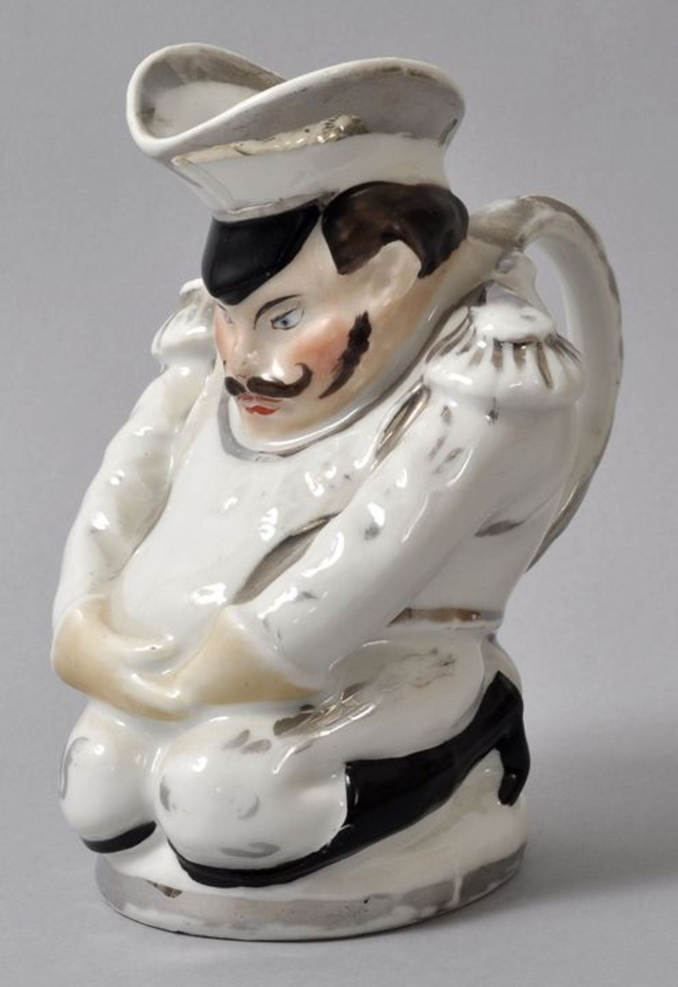 Figurenkrug/ Toby jug, England (?), 19. Jh.Porzellan, sparsam polychrom bemalt mit Silberhöhungen.