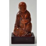 Figur eines Mönchs, ChinaGefärbtes Horn von rötlicher Farbe, geschnitzt, H. 14 cm. Holzsockel.