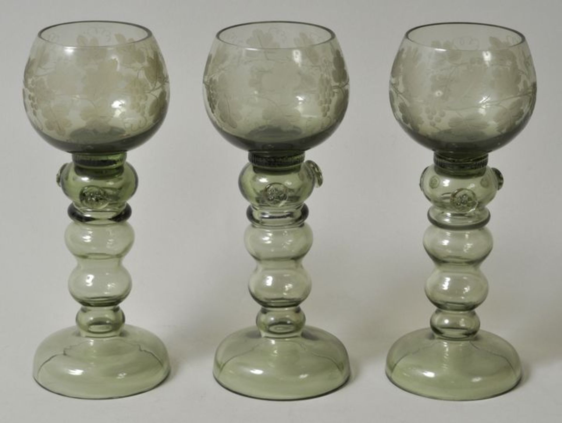 Drei Römer, 2. H. 19. Jh.Grünes Glas, Hohlschaft mit drei Balustern, drei aufgeschmolzene Noppen,