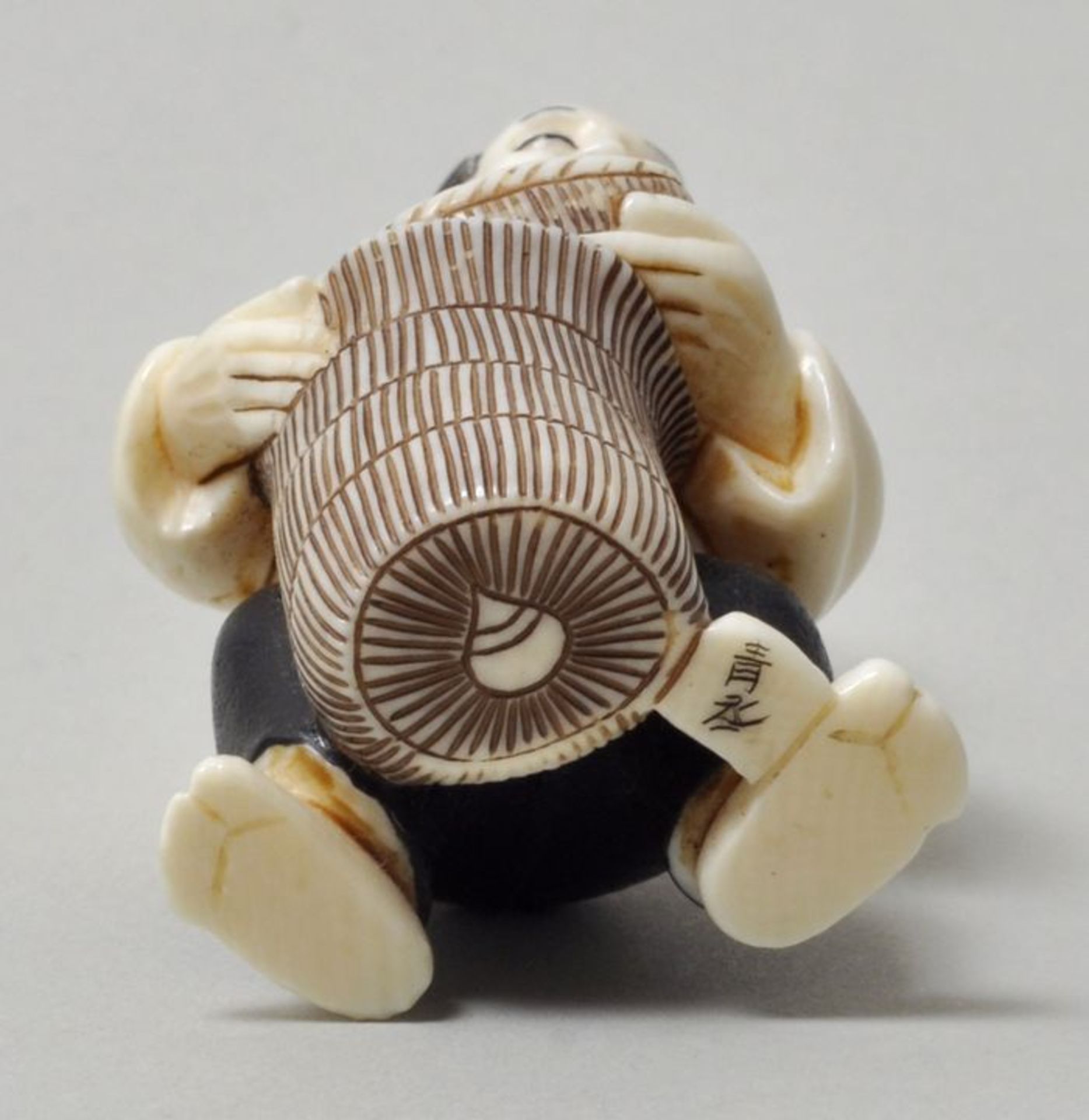 Netsuke, Japan, 20. Jh.Mann mit zwei Korbgefäßen. Elfenbein, geschnitzt, Details farbig, sign. ( - Bild 2 aus 2