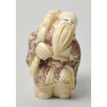 Okimono-Netsuke, Japan, 20. Jh.Elfenbein, geschnitzt, Binnengravur zweifarbig eingefärbt. Glücksgott