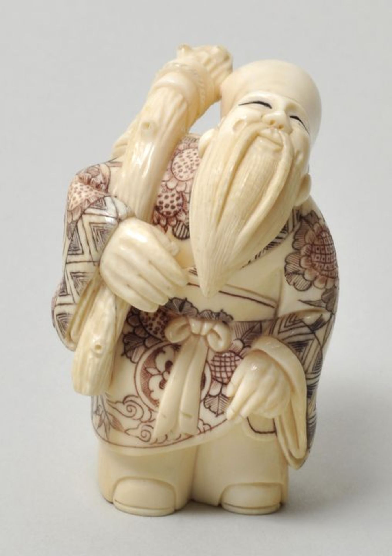 Okimono-Netsuke, Japan, 20. Jh.Elfenbein, geschnitzt, Binnengravur zweifarbig eingefärbt. Glücksgott