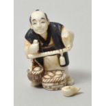 Netsuke, Japan, 19./ 20. Jh.Elfenbein, geschnitzt, schwarz und dunkelgrün bemalt: ein Händler mit