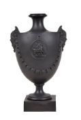 A Neale & Co. black basalt urn with mask handles, circa 1780, sprigged with swags and a medallion of