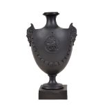 A Neale & Co. black basalt urn with mask handles, circa 1780, sprigged with swags and a medallion of