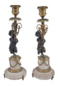 A pair of French patinated and parcel gilt bronze and marble mounted candlesticks