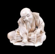 ϒ HOMIN: A Japanese carved ivory Okimono depicting a drummer seated cross-legged on a mat