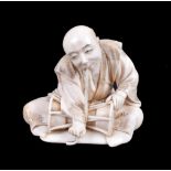 ϒ HOMIN: A Japanese carved ivory Okimono depicting a drummer seated cross-legged on a mat