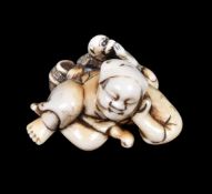 ϒ A Japanese carved Ivory Netsuke of a reclining sarumawashi dressed in typical garb and asleep