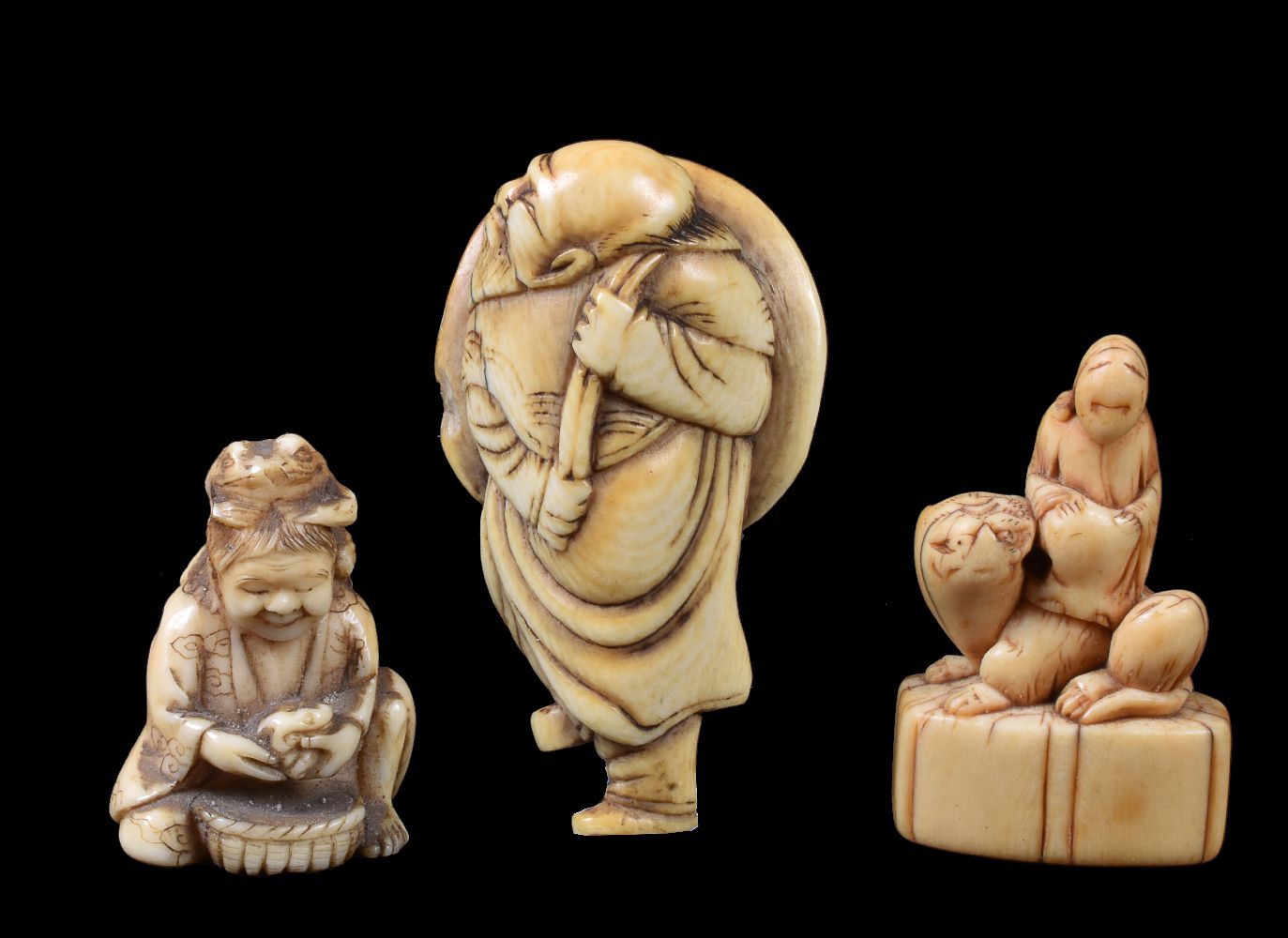 ϒ An Ivory Japanese Netsuke of a bearded sage carrying a large hat over his shoulder