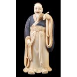 ϒ A Japanese Ivory Okimono of a Nobleman standing in voluminous robes and holding up a spoon