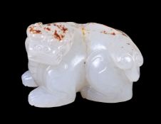 A Chinese white jade or pale celadon and russet carving of a lion