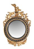 A carved giltwood and ebonised circular convex wall mirror