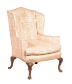 A carved beech and upholstered wing armchair