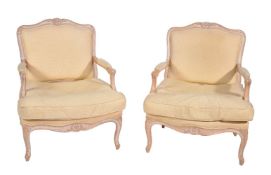 A pair of carved limed beech and upholstered armchairs