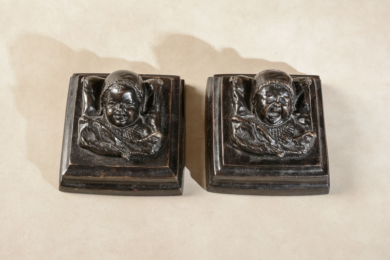 A pair of patinated bronze reliefs cast as infants' heads - Image 2 of 2