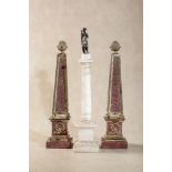 A pair of painted faux porphyry and parcel gilt metal models of obelisks